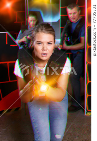 satisfied girl with laser pistol playing laser tag with friends satisfied girl with laser pistol playing laser tag with friends 77705531