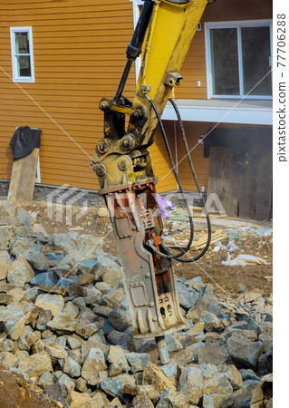 Large jackhammer smashing rocks in the new laying road around home 77706288