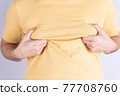 Fat man holding excessive fat boobs isolated grey background. 77708760