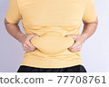 Fat man holding excessive fat belly isolated grey background. 77708761
