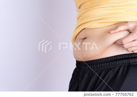 Fat man holding excessive fat belly isolated grey background. 77708762