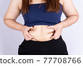 Fat woman holding excessive fat belly isolated grey background. 77708766
