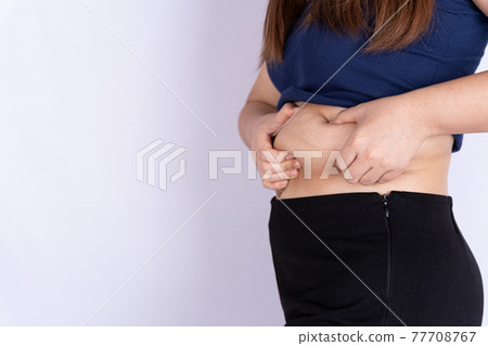 Fat woman holding excessive fat belly isolated grey background. 77708767