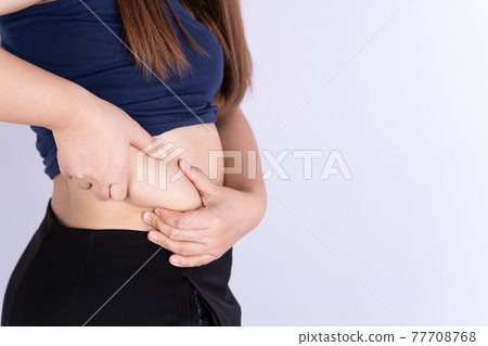 Fat woman holding excessive fat belly isolated grey background. 77708768