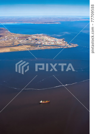 Aerial view of a cargo ship and a small port town in the Arctic 77709588