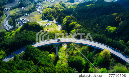 An aerial road that draws a beautiful curve like a compass taken with a drone in the fresh green! 77710508