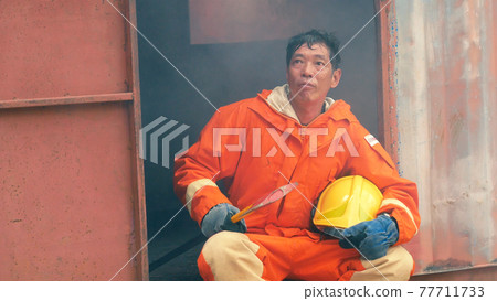 Firefighter fighting with flame using fire hose chemical water foam spray engine. Fireman wear hard hat, body safe suit uniform for protection. Rescue training in fire fighting extinguisher 77711733