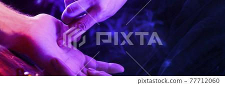 Witch is a fortune teller reading good luck close-up. Fortune teller guides the lines on the client's hand in neon light 77712060