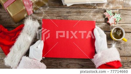 Composition of santa claus holding red blank board and christmas presents 77714660