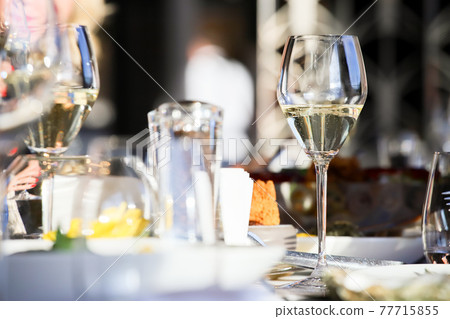 Glassware, glasses for white wine on a table in a restaurant. Banquet, cutlery, table setting. 77715855