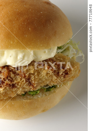 A hamburger sandwiched between plenty of tartar sauce and fried white fish is photographed on a white background (front, bird's-eye view) A hamburger sandwiched between plenty of tartar sauce and fried white fish is photographed on a white background (front, bird's-eye view) 77718648