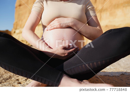 close-up photo. a pregnant woman sits on the seashore close-up photo. a pregnant woman sits on the seashore 77718848