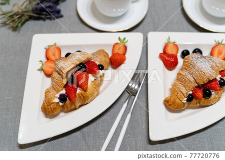 Croissant fruit sandwich served on a white plate 77720776