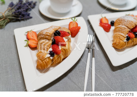 Croissant fruit sandwich served on a white plate 77720778