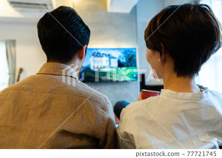 Couple watching on-demand delivery in the living room Couple watching on-demand delivery in the living room 77721745
