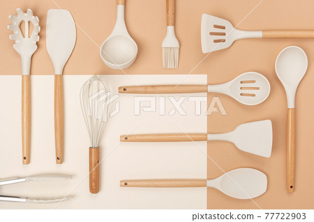 Pattern made from cooking utensil set. Silicone kitchen tools with wooden handle on beige background. Top view Flat lay 77722903