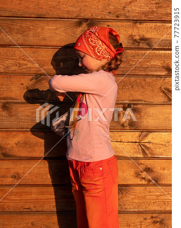 Kid using smartwatch outdoor on wooden background sunny day. Child talking on vdeo call on smartphone. Kid using smartwatch outdoor on wooden background sunny day. Child talking on vdeo call on smartphone. 77723915