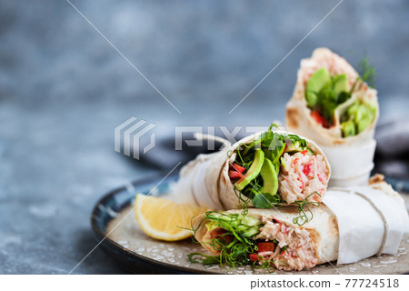 Fresh and healthy wrapped tortilla with crab salad, cucumber, avocado, pepper and green herbs 77724518