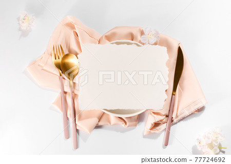 Beautifully decorated table with white plates, golden apple cutlery and flowers on beige tablecloths 77724692