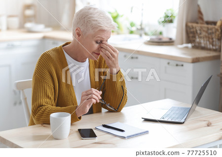 Tired mature woman freelancer working from home, using laptop 77725510