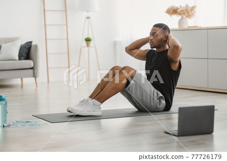 Sporty Black Man Doing Sit-Ups Exercise At Laptop Indoor, Side-View Sporty Black Man Doing Sit-Ups Exercise At Laptop Indoor, Side-View 77726179