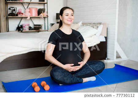 Pregnant woman exercing yoga at home. Pregnancy yoga and fitness. 77730112