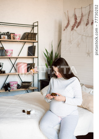 Pregnant woman holding medicine. Girl holding pills in her hands. 77730202