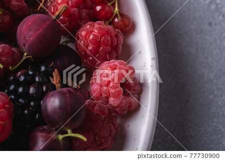 Tasty fresh ripe raspberry, blackberry, gooseberry and red currant berries in plate, healthy food fruit on stone concrete background, angle view macro Tasty fresh ripe raspberry, blackberry, gooseberry and red currant berries in plate, healthy food fruit on stone concrete background, angle view macro 77730900