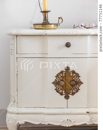 Close-up of vintage wooden bedside table with metal fitment. Candle and glasses for reading for cosy atmosphere. Close-up of vintage wooden bedside table with metal fitment. Candle and glasses for reading for cosy atmosphere. 77731146