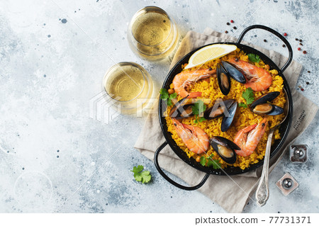 Traditional spanish seafood paella in pan with chickpeas, shrimps, mussels, squid on light grey concrete background. Top view with copy space Traditional spanish seafood paella in pan with chickpeas, shrimps, mussels, squid on light grey concrete background. Top view with copy space 77731371