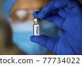 Doctor holding and looking covid-19 vaccine in hospital 77734022