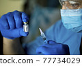 Doctor preparing injection with covid-19 vaccine at hospital 77734029