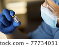 Doctor holding and looking covid-19 vaccine in hospital 77734031