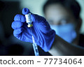 Doctor pulling vaccine liquid from vial to vaccinate man 77734064