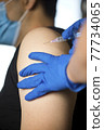Doctor injecting vaccine into arm of patient 77734065