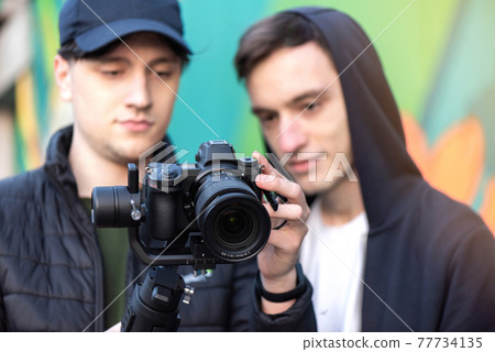 Two men looking into the camera screen Two men looking into the camera screen 77734135