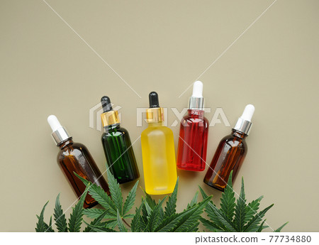 Cannabis cbd oil and green leaves on grey background. Marijuana extract in cosmetology 77734880
