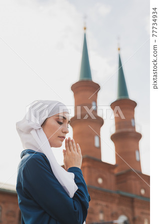 Muslim woman prayer wear hijab fasting pray to allah on mosque background Muslim woman prayer wear hijab fasting pray to allah on mosque background 77734934