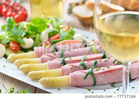 Delicious spring salad with asparagus rolled in cooked ham served with a young dry white wine Delicious spring salad with asparagus rolled in cooked ham served with a young dry white wine 77737184