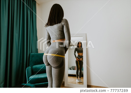 attractive slim Woman Measuring body With Tape at home attractive slim Woman Measuring body With Tape at home 77737289