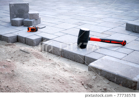 The master in yellow gloves lays paving stones The master in yellow gloves lays paving stones 77738578