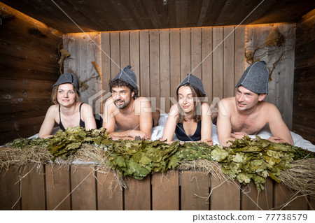 Company of friends lying on wooden bench covered with hay  Company of friends lying on wooden bench covered with hay  77738579