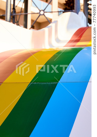 Rainbow multicoloured slide in aqua park in kids playground. Summer time activity outdoors with Rainbow multicoloured slide in aqua park in kids playground. Summer time activity outdoors with 77740993