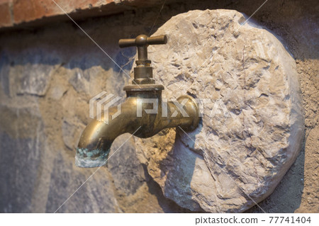 antique bronze faucet embedded in piece of stone. hard water Plumbing in rock antique bronze faucet embedded in piece of stone. hard water Plumbing in rock 77741404