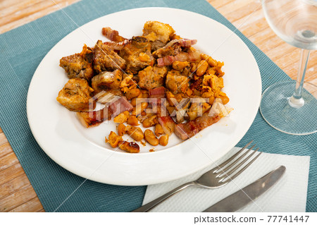 Tasty dish consisting in slices of roast pork on plate with beans 77741447