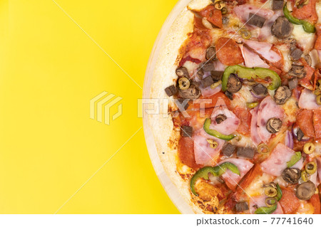 Delicious large pizza with veal and mushrooms on a yellow background Delicious large pizza with veal and mushrooms on a yellow background 77741640