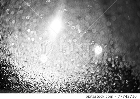 Raindrops on the glass at night. The lanterns are shining. Black and white bokeh. Car glass. Defocus. 77742716
