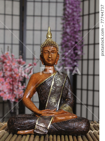 Buddha Statue in Asian Style Room With Cherry Blossoms in Background Buddha Statue in Asian Style Room With Cherry Blossoms in Background 77744737