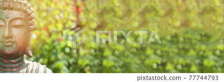 Buddha Statue in Outdoor Garden With Blurred Background 77744793