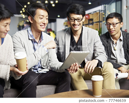 young asian businesspeople sitting in sofa looking at tablet computer, happy and smiling 77746639